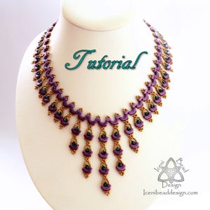 Op de afbeelding: Een paarse en gouden kralenketting met een cascade-ontwerp. De ketting is op een witte mannequinbuste. Het woord "Tutorial" is in cursief boven de ketting geschreven.