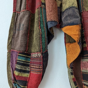 Może przedstawiać: Spodnie patchwork w r&oacute;żnych kolorach, w tym brązowym, czerwonym, fioletowym i zielonym. Spodnie mają luźny, wygodny kr&oacute;j z marszczonym kostką. Tkanina ma mieszankę faktur i wzor&oacute;w, tworząc niepowtarzalny, bohemiczny styl.