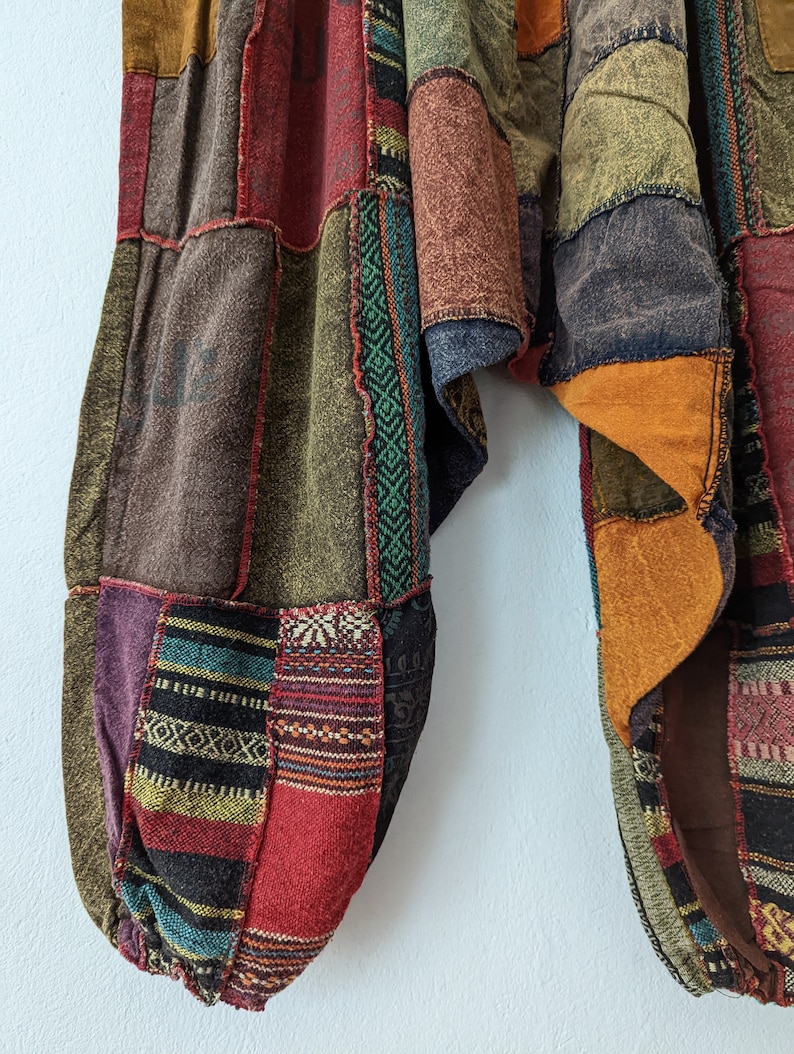 Może przedstawiać: Spodnie patchwork w r&oacute;żnych kolorach, w tym brązowym, czerwonym, fioletowym i zielonym. Spodnie mają luźny, wygodny kr&oacute;j z marszczonym kostką. Tkanina ma mieszankę faktur i wzor&oacute;w, tworząc niepowtarzalny, bohemiczny styl.