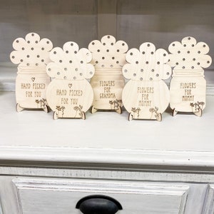 May include: Five wooden flower pot stands with different messages. The messages are "Hand Picked For You", "Hand Picked For You", "Flowers For Grandma", "Flowers For Mommy", and "Flowers For Mommy".