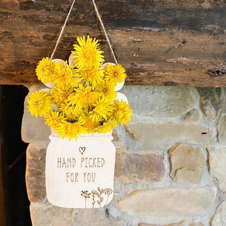 May include: A wooden cutout of a mason jar with a bunch of yellow dandelions inside. The jar has the text "Hand Picked For You" written on it.
