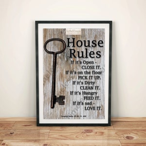 May include: A framed print with a rustic wood background and a large antique key. The print features the text "House Rules" and a list of rules: "If it's Open - CLOSE IT. If it's on the floor PICK IT UP. If it's Dirty CLEAN IT. If it's Hungry FEED IT. If it's sad - LOVE IT."