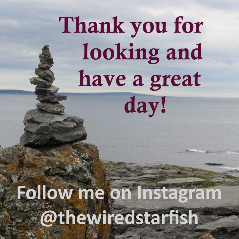 Op de afbeelding: Een landschapsfoto met een stapel grijze stenen op een rots, met de zee en de lucht op de achtergrond. De tekst luidt: "Thank you for looking and have a great day!" en "Follow me on Instagram @thewiredstarfish".
