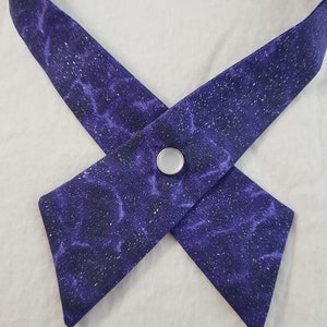 May include: A purple necktie with a sparkly, galaxy-like pattern and a white button.