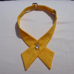 May include: A yellow fabric necktie with a white button closure. The tie is tied in a bow shape.