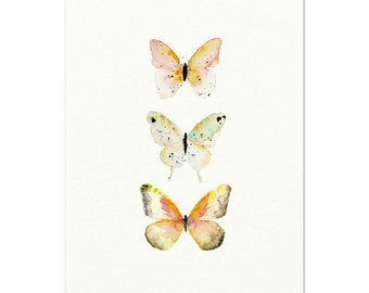 Peut inclure: Trois papillons aquarelle disposés verticalement sur un fond blanc. Le papillon du haut est pêche et orange, le papillon du milieu est blanc avec des accents verts, et le papillon du bas est orange et jaune.