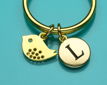May include: Gold key chain with a small bird charm and a round charm with the letter L.