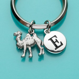 Op de afbeelding: Zilveren sleutelhanger met een kameelhanger en een ronde hanger met de letter E in zwart.
