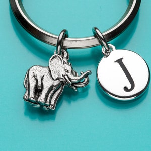 Puede incluir: Llavero de plata con un pequeño encanto de elefante y un encanto redondo con la letra J.