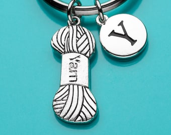 May include: Silver keychain with a yarn ball charm and a letter Y charm. The yarn ball charm has the word "yarn" written on it.
