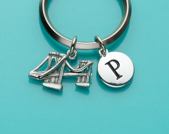 Pode incluir: Chaveiro de prata com um charme da Golden Gate Bridge e um charme com a letra "P" nele.
