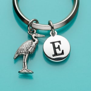 May include: Silver keychain with a bird charm and a round charm with the letter E in black.