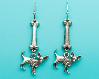 May include: Silver dangle earrings featuring a bone charm with a small silver chihuahua charm hanging from it.