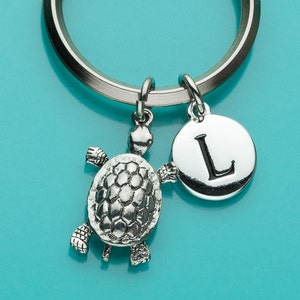 May include: Silver keychain with a turtle charm and a round charm with the letter L on it.