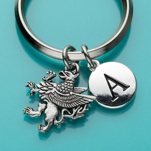 May include: Silver keyring with a silver griffin charm and a silver charm with the letter A.