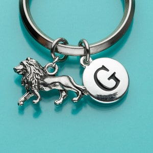 May include: Silver keychain with a lion charm and a round charm with the letter G.