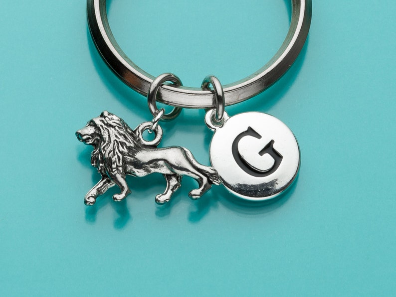 May include: Silver keychain with a lion charm and a round charm with the letter G.