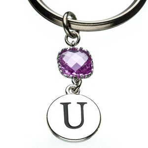 May include: A silver keychain with a purple rhinestone charm and a silver charm with the letter U.