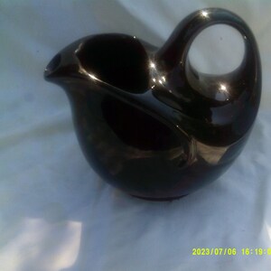 May include: A black ceramic pitcher with a unique spout and handle. The pitcher has a glossy finish.