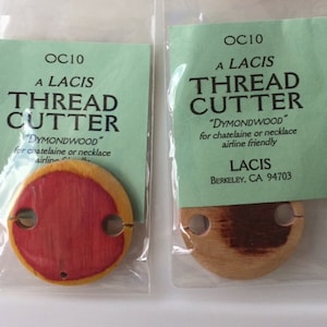May include: A wooden thread cutter labeled "OC10 A LACIS THREAD CUTTER" with the text "DYMONDWOOD" for chatelaine or necklace airline friendly LACIS BERKELEY, CA 94703".