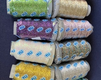 May include: Twelve spools of metallic thread with glitter. The spools are arranged in a vertical stack. The spools are in various colors, including red, green, gold, purple, white, silver, and blue.