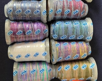 May include: A collection of 11 spools of thread in various colors, including beige, white, blue, purple, cream, multi-colored, and red. Each spool has the text "YLI" printed on it.