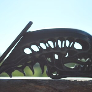May include: A black phone stand shaped like an alien skull with a phone propped up against it.