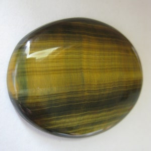 May include: A smooth, oval-shaped tiger's eye gemstone with a golden brown and black striped pattern.