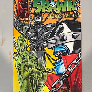 May include: A comic book cover featuring a green and black character with a skull on its head, a blue and red character with a spiked helmet, and a black and gray character with a cape. The title of the comic is "The Spawn Who Laughs".