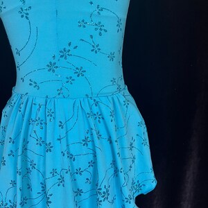 May include: A light blue dance dress with a floral pattern and glitter accents. The dress has a fitted bodice and a flared skirt.