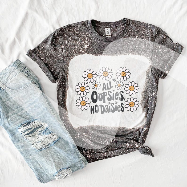May include: A black and white bleached t-shirt with a graphic design of daisies and the text "All * Oops* No Daisies".