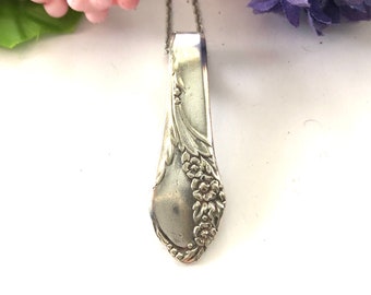 Puede incluir: Un collar de plata con un colgante hecho de una cuchara de plata vintage con un diseño floral.