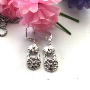 May include: A pair of silver earrings with a floral design. The earrings are made from repurposed silverware and have a unique, vintage look.