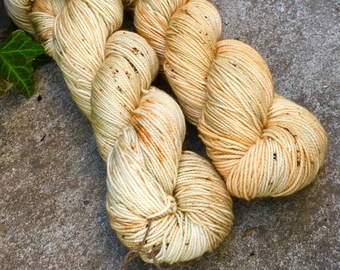 May include: Two skeins of yarn in a cream color with orange and brown speckles. The yarn is soft and fluffy and would be perfect for knitting or crocheting.