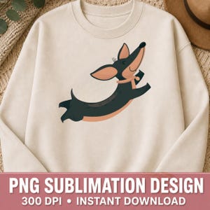 Peut inclure: Sweat-shirt crème avec un teckel de dessin animé en plein saut. Le chien est noir et marron avec un collier rose. Le bas de l'image contient le texte "PNG SUBLIMATION DESIGN 300 DPI • INSTANT DOWNLOAD".