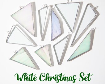 May include: A set of ten white iridescent glass triangle ornaments with silver metal frames. The ornaments are arranged in a circular pattern on a white background. The text "White Christmas Set" is written in green cursive below the ornaments.