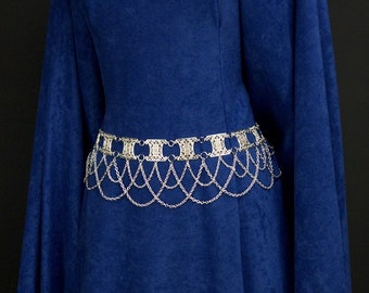 May include: A royal blue velvet dress with a silver chain belt. The belt has a decorative design with a series of connected links.