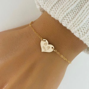 May include: A gold chain bracelet with a heart-shaped charm featuring a paw print design.