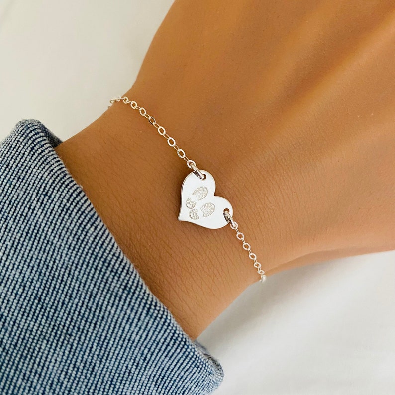May include: A silver chain bracelet with a heart-shaped charm featuring a paw print design.