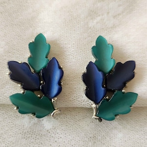 May include: A pair of blue and green leaf-shaped earrings. The earrings are made of metal and have a shiny finish.