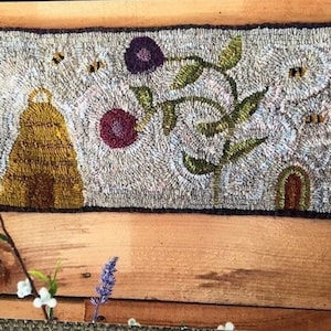 May include: A hand-stitched rug depicting a beehive, flowers, and bees. The rug is made with a variety of colors, including yellow, brown, green, and purple.