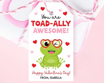 Peut inclure: Une étiquette cadeau de Saint-Valentin avec une grenouille verte portant des lunettes en forme de cœur. L'étiquette indique "You are TOAD-ALLY AWESOME!" et "Happy Valentine's Day!" avec un nom en bas. Des cœurs rouges et roses décorent l'étiquette.