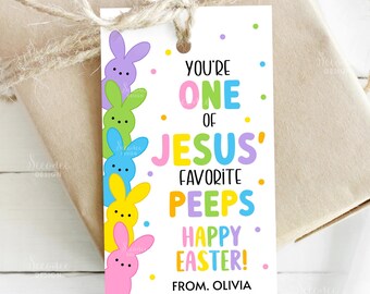 May include: A white Easter gift tag with colorful text and bunny illustrations. The tag reads "YOU'RE ONE OF JESUS' FAVORITE PEEPS HAPPY EASTER!" with the name "OLIVIA" at the bottom. The tag is tied to a wrapped gift.