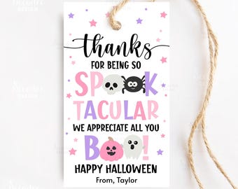 May include: A white Halloween gift tag with a jute string. The tag features the words "thanks" and "Happy Halloween" in black, along with the phrase "for being so Spooktacular." Pink, purple, and white accents include stars, a skull, spider, pumpkin, and ghost.