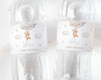 May include: Two clear plastic water bottles with white labels. The labels feature a watercolor illustration of a teddy bear holding balloons, clouds, and snowflakes. The text on the labels reads "Hailey's Baby Shower".