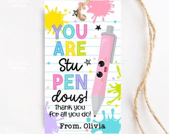 May include: A white gift tag with a pink pen illustration and the words "YOU ARE StuPENdous!" in colorful letters. The tag includes the text "Thank you for all you do! From. Olivia" and colorful paint splatters.