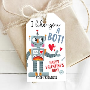 May include: A Valentine's Day gift tag with a cartoon robot illustration. The tag reads "I like you a bot!" with "Happy Valentine's Day!" and "From Charlie" below the robot. The robot is gray, orange, and red.
