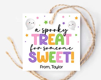 May include: A white square gift tag with the text "a spooky TREAT for someone SWEET!" in colorful letters. Two cartoon ghosts and stars decorate the tag. The tag is tied with a natural twine.