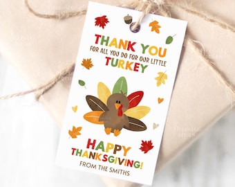 Könnte beinhalten: Ein weißes Thanksgiving-Geschenkanhänger mit einer Cartoon-Truthahn und Herbstblättern. Der Text lautet "Danke" und "Fröhliches Thanksgiving!" Das Etikett ist mit Bindfaden an einem verpackten Geschenk befestigt.