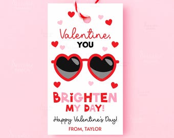 May include: A white Valentine's Day gift tag with red and pink hearts. The tag features heart-shaped sunglasses and the text "Valentine, YOU, BRIGHTEN MY DAY! Happy Valentine's Day! FROM, TAYLOR."